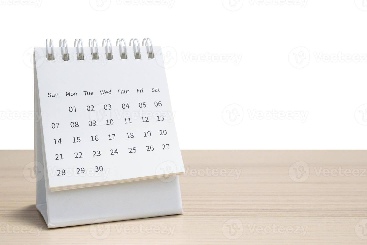 calendário de mesa branco no tampo da mesa de madeira isolado no fundo branco foto