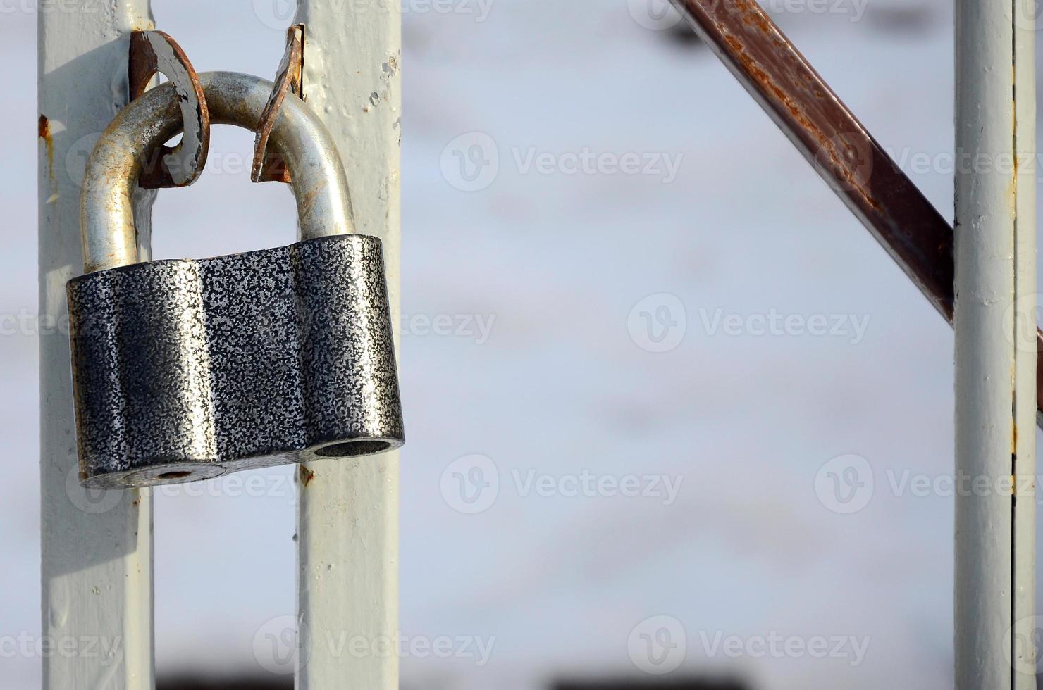 um grande cadeado cinza está pendurado em um portão de metal foto