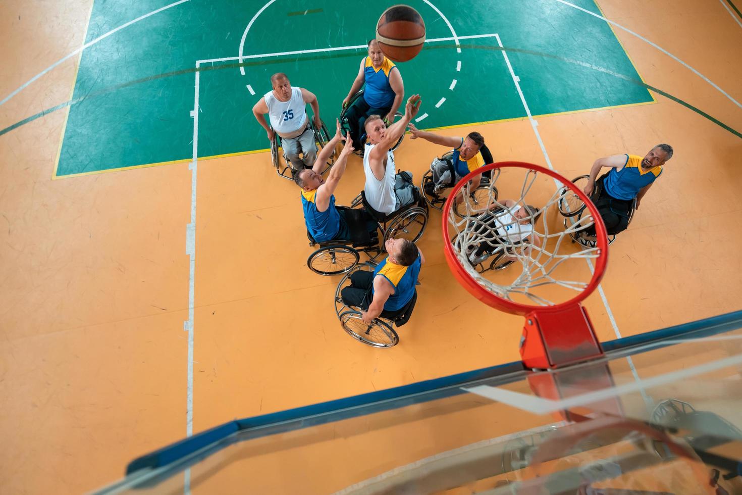 guerra com deficiência ou veteranos de trabalho mistos de raça e idade equipes de basquete em cadeiras de rodas jogando uma partida de treinamento em um ginásio de esportes. conceito de reabilitação e inclusão de pessoas com deficiência. foto