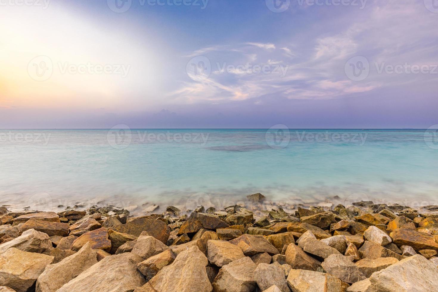 nascer do sol no disjuntor de ondas de praia, paisagem marinha com rochas e efeito de seda na água, céu pôr do sol de fantasia foto