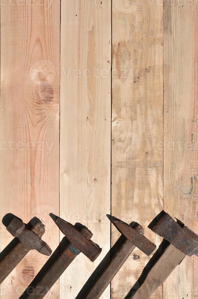 alguns martelos enferrujados estão em uma mesa de madeira em uma oficina foto