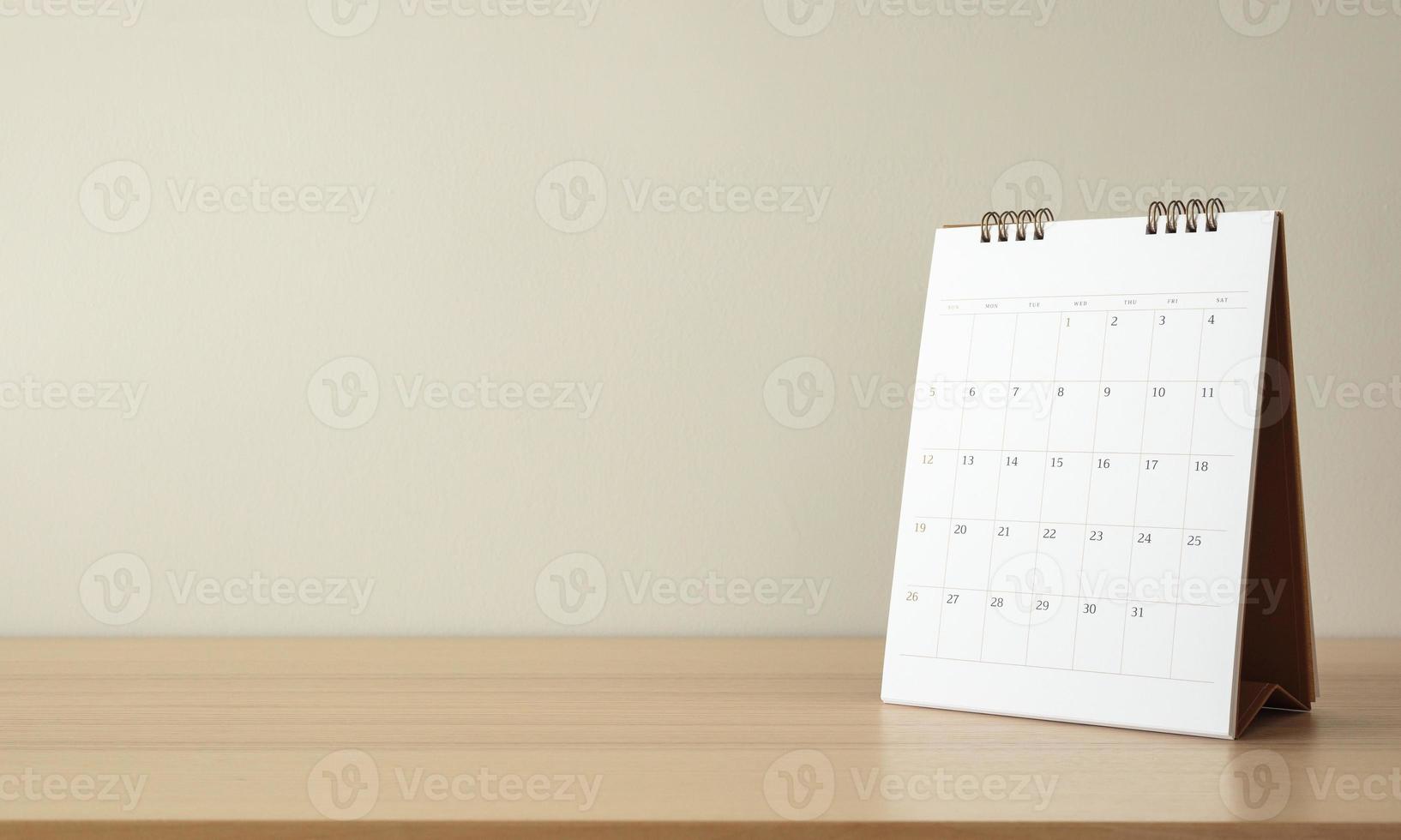 página do calendário fechar na mesa de madeira com fundo de parede branca conceito de reunião de planejamento de negócios foto