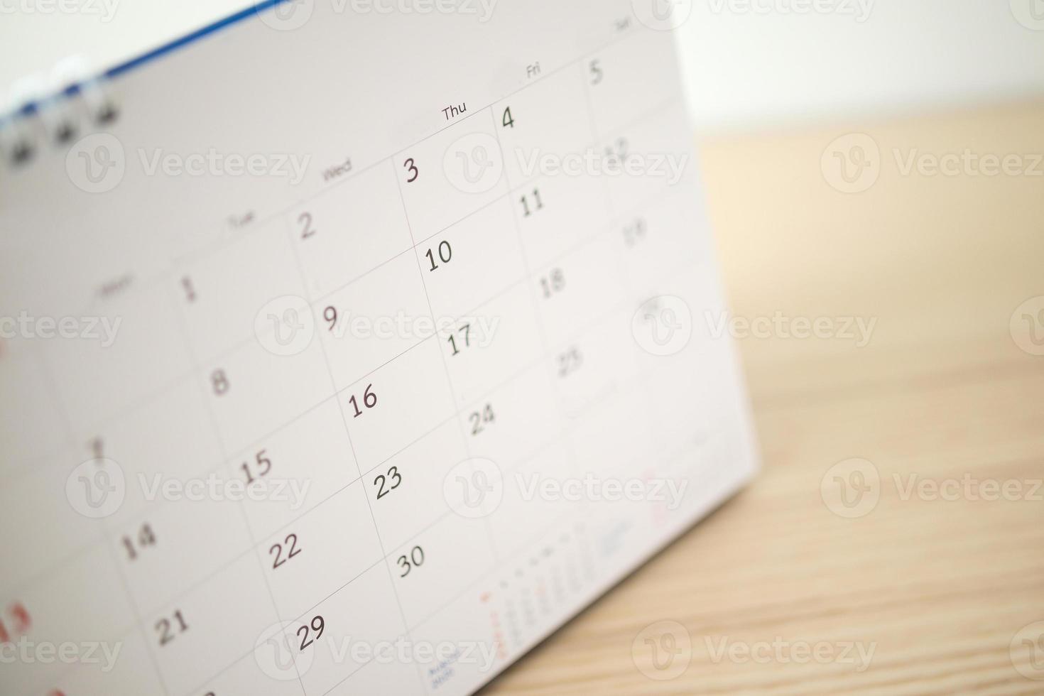 página do calendário fechar na mesa de madeira com fundo de parede branca foto