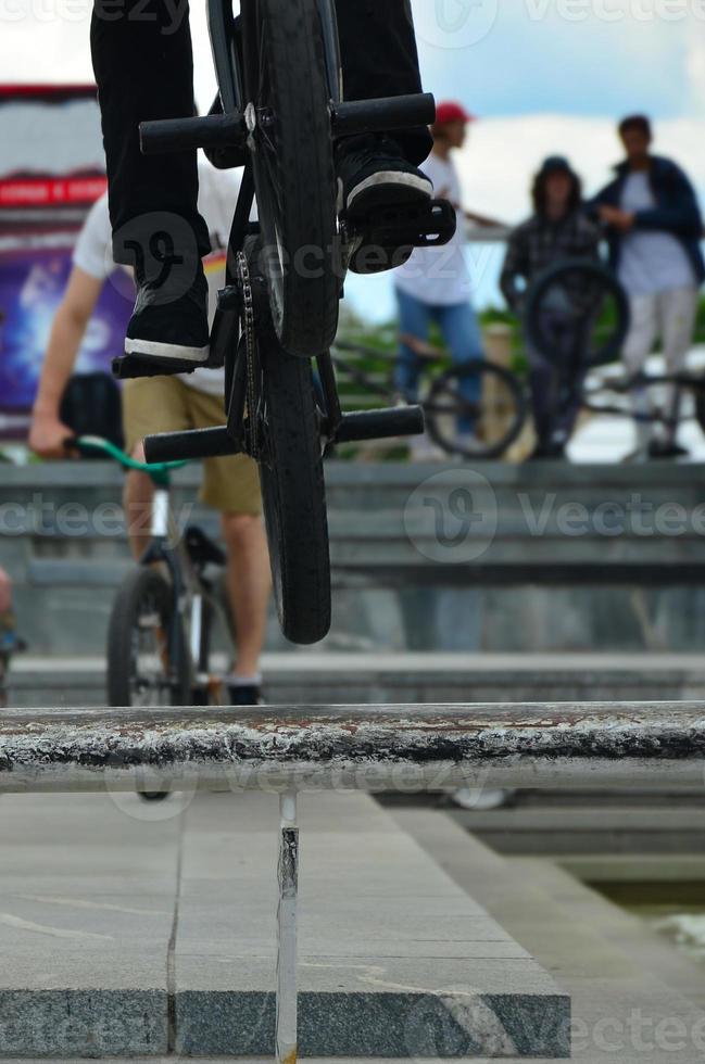 um ciclista salta sobre um cano em uma bicicleta bmx. muitas pessoas com bicicletas ao fundo. conceito de esportes radicais foto