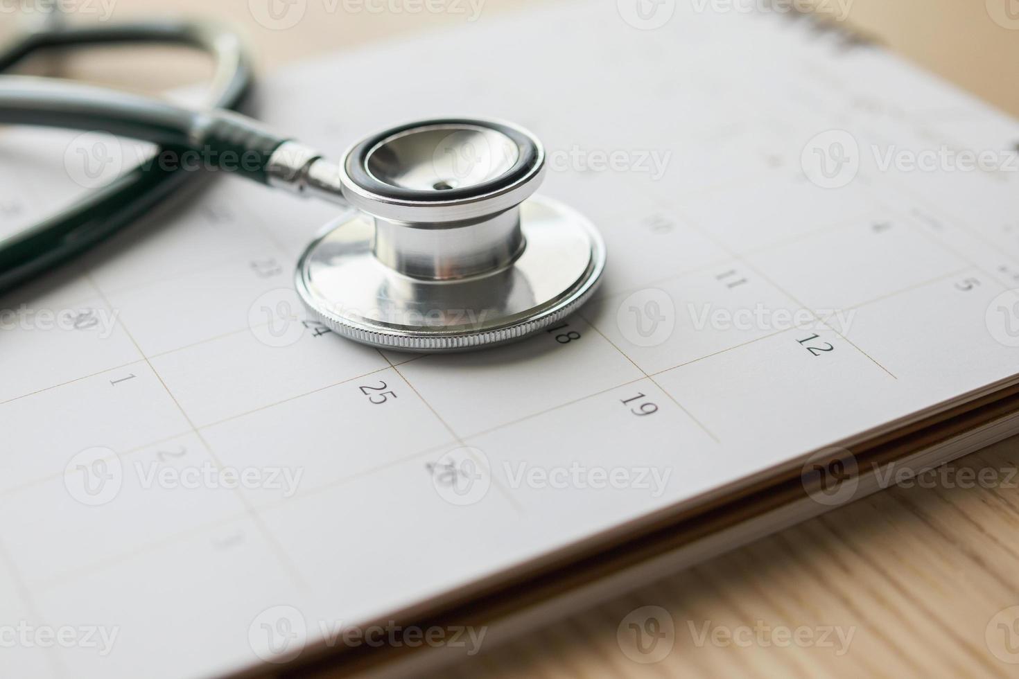estetoscópio com data de página de calendário no conceito médico de consulta médica de fundo de mesa de madeira foto