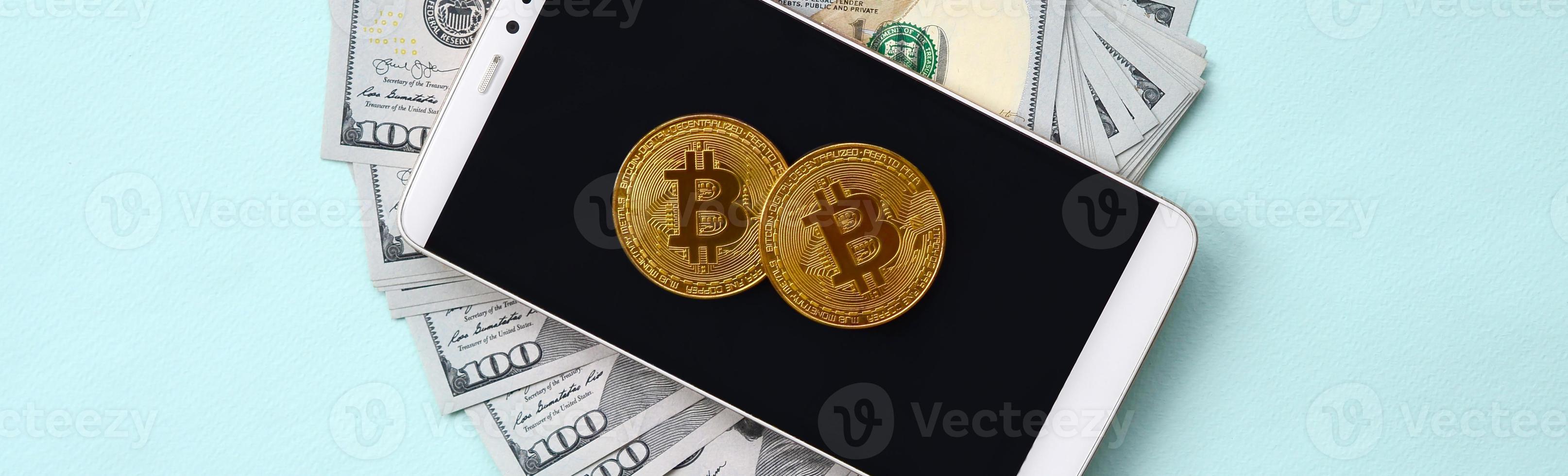 bitcoins está em um smartphone e notas de cem dólares em um fundo azul claro foto