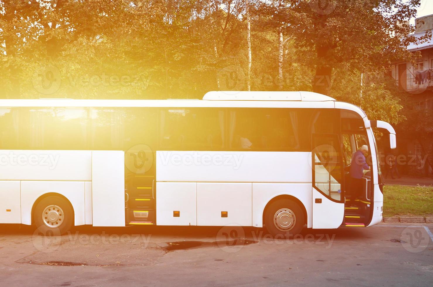 ônibus turístico branco para excursões. o ônibus está estacionado em um estacionamento perto do parque foto