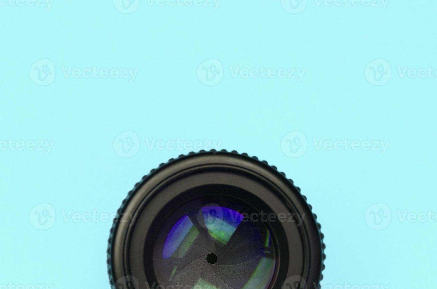 a lente da câmera com uma abertura fechada está no fundo da textura do papel de cor azul pastel de moda foto