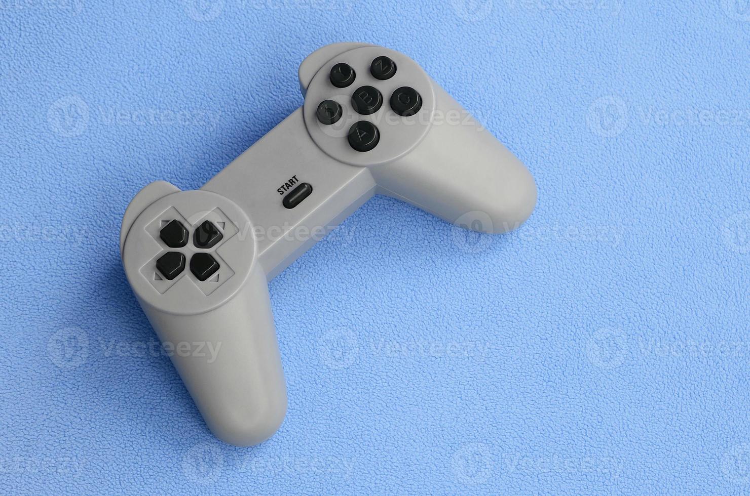 jogando o conceito de jogos. joystick de almofada única encontra-se no cobertor de tecido de lã azul peludo. controlador para jogos de vídeo em uma textura de fundo de material de lã macia azul claro foto