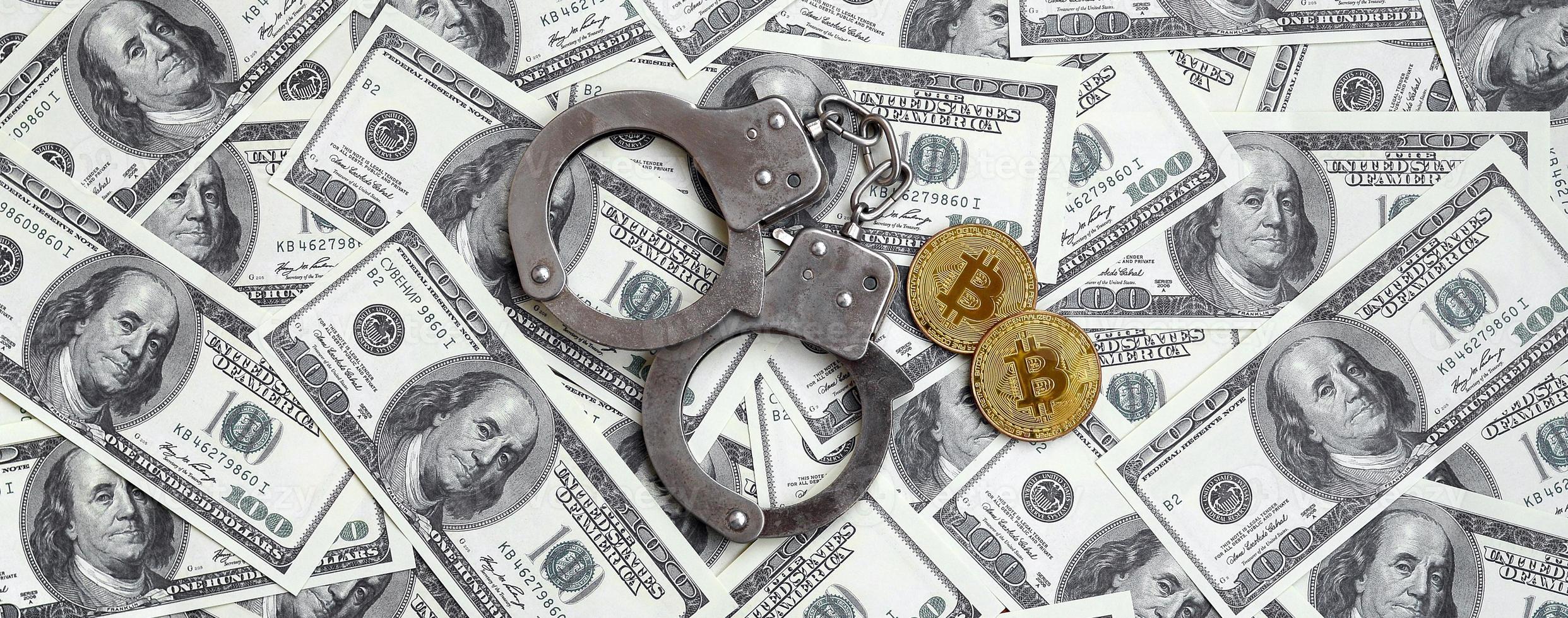 algemas da polícia e bitcoins estão em um grande número de notas de dólar. o conceito de problemas com a lei durante as operações ilegais de mineração de criptomoedas e bitcoin foto