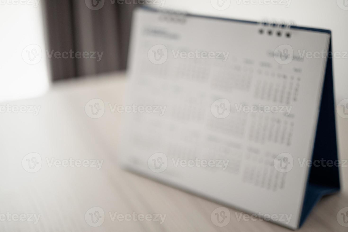 desfoque a página do calendário de perto no fundo da mesa de madeira conceito de reunião de planejamento de negócios foto