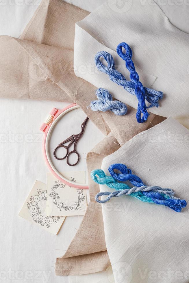 conjunto de bordados. tecido de linho, padrões de bordado, bastidor de bordar, linhas e agulhas coloridas. foto