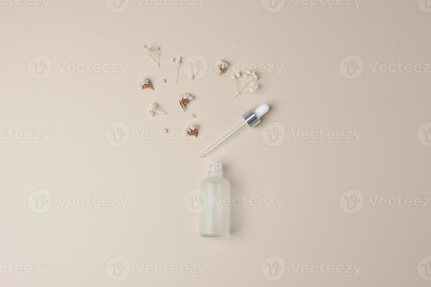 frasco cosmético com flores sobre fundo bege pastel. postura plana, copie o espaço foto