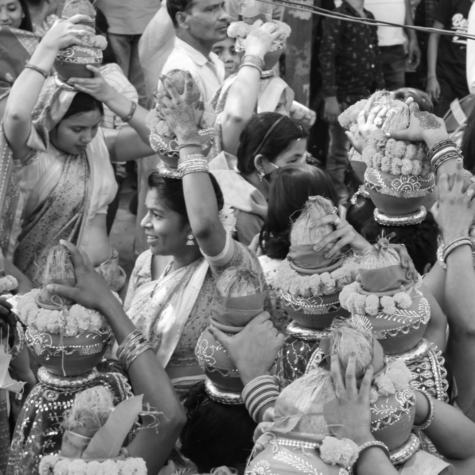 delhi, índia, 03 de abril de 2022 - mulheres com kalash na cabeça durante o templo jagannath mangal kalash yatra, devotos hindus indianos carregam potes de barro contendo água sagrada com coco no topo-preto e branco foto