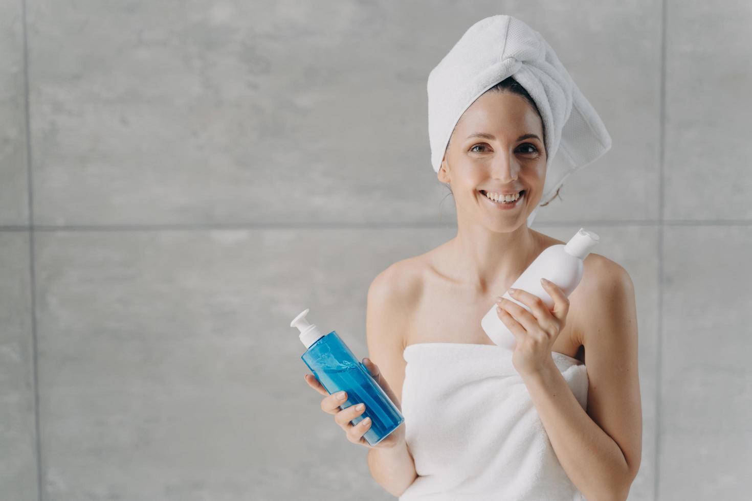 pele, publicidade de cosméticos para cuidados com o cabelo. mulher feliz detém garrafas de maquete com gel de banho, shampoo foto