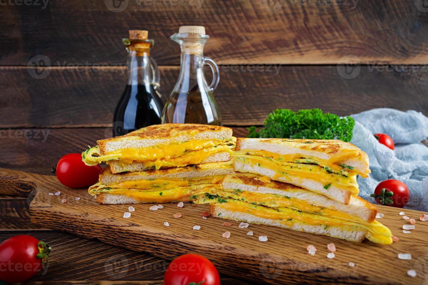 rabanada assada com presunto, ovo, ervas e queijo cheddar. delicioso sanduíche de café da manhã grelhado foto