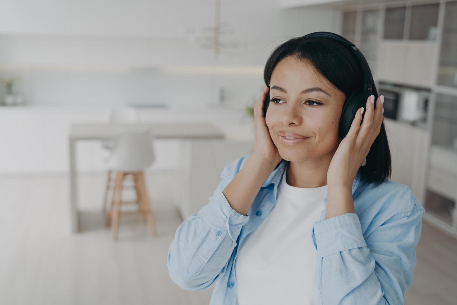 mulher feliz em fones de ouvido ouve música, podcast ou livro de áudio desfrutando de som perfeito em casa foto