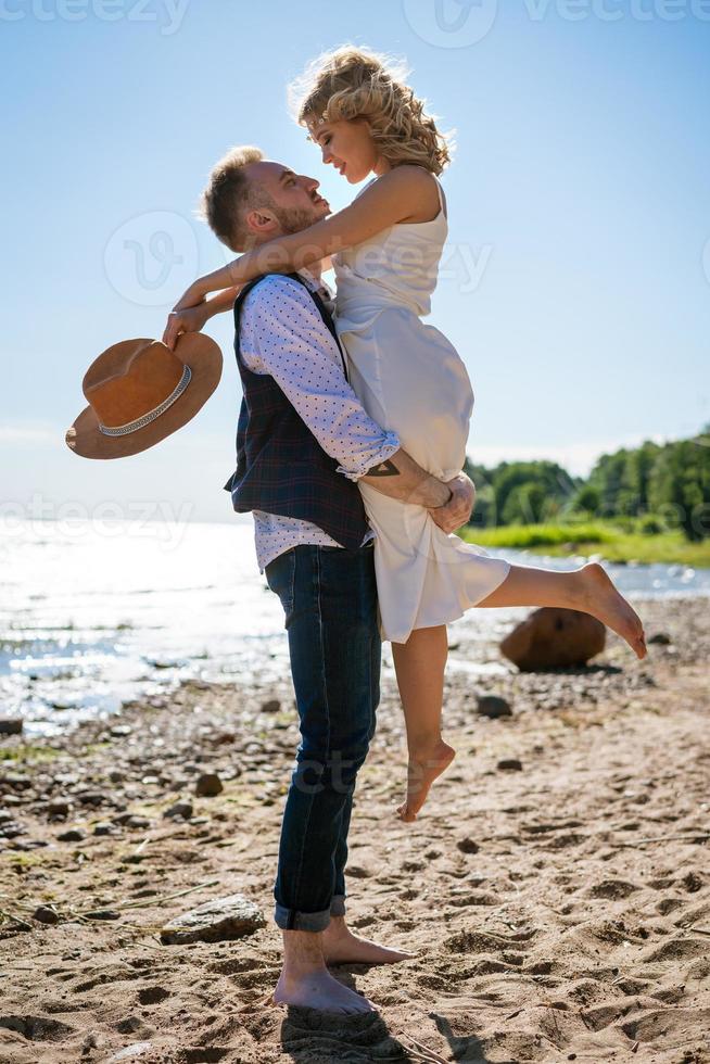 feliz jovem casal lindo em um abraço na costa do mar foto