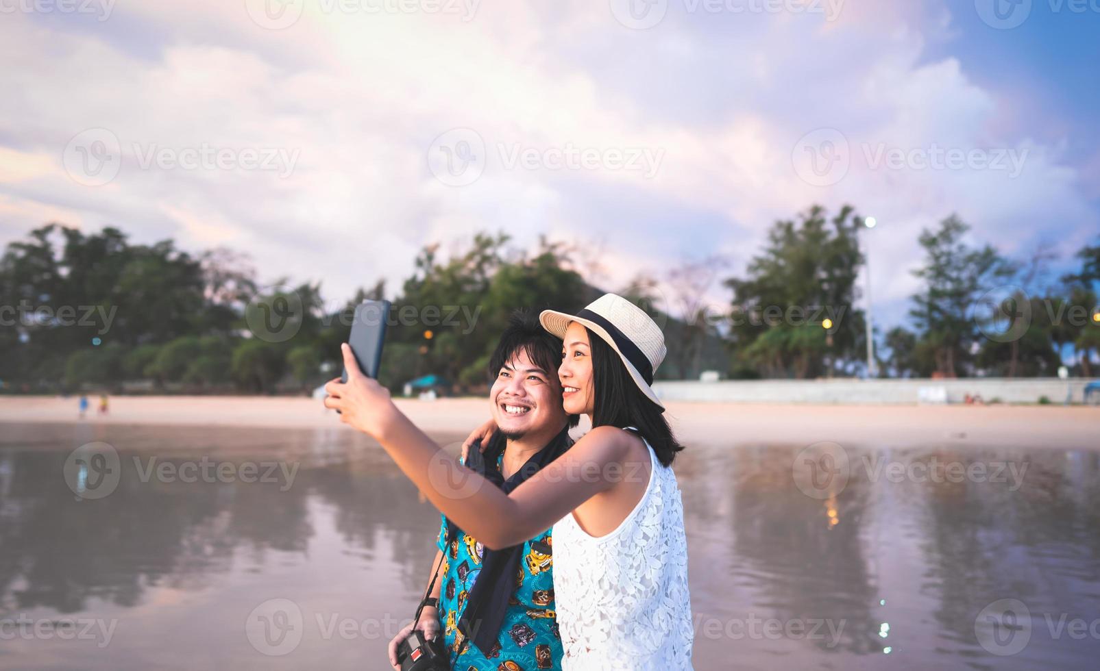 relaxe adultos asiáticos selfie pelo celular no mar da praia. foto