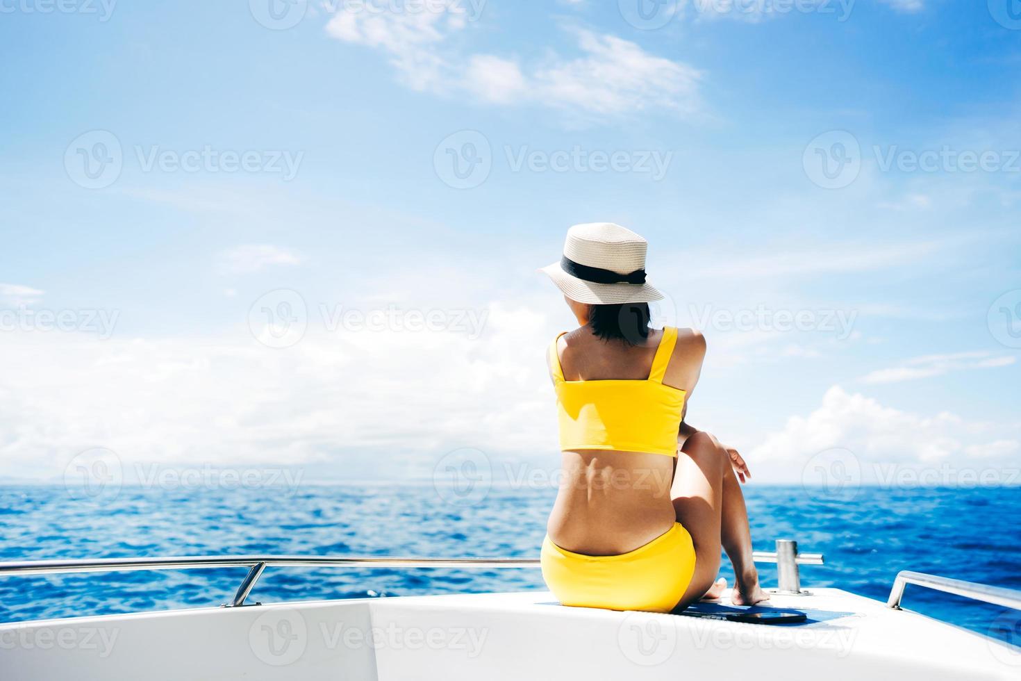 jovem adulta viajando sente-se no barco à vela com céu azul e mar foto