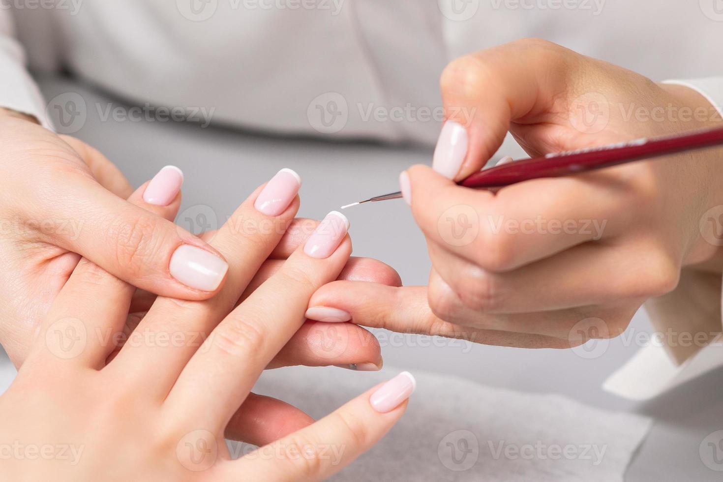 mulher recebendo manicure francesa por esteticista foto