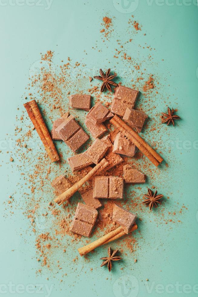 fatias de chocolate escuro com canela e especiarias em um fundo verde pastel. foto