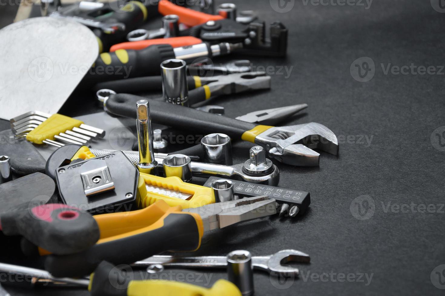 kit de ferramentas de faz-tudo na mesa de madeira preta. muitas chaves e chaves de fenda, empilhadeiras e outras ferramentas para qualquer tipo de reparo ou construção. ferramentas de reparador foto