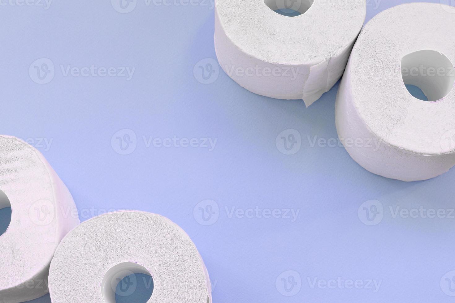 conceito de compras de pânico pandêmico de coronavírus. alguns novos rolos de papel higiênico em fundo azul claro. composição minimalista plana leiga com espaço de cópia foto