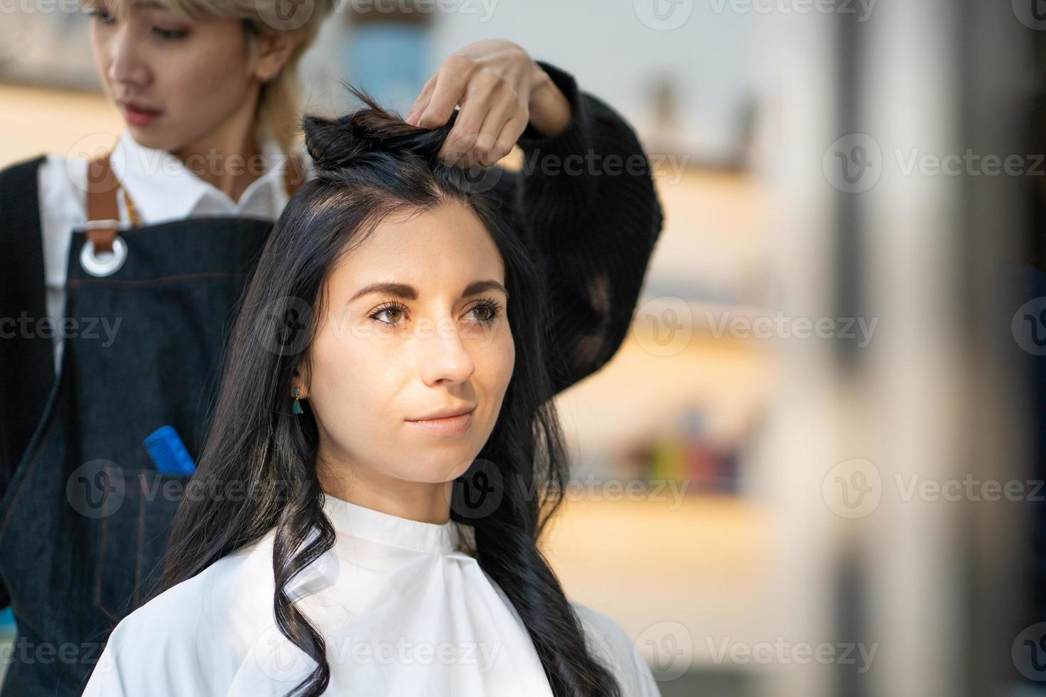 mulheres caucasianas com cabelo elegante enquanto cortam o cabelo e usam máscara facial cirúrgica enquanto estilizam o cabelo para o cliente. ocupação profissional, serviço de beleza e moda novo normal foto
