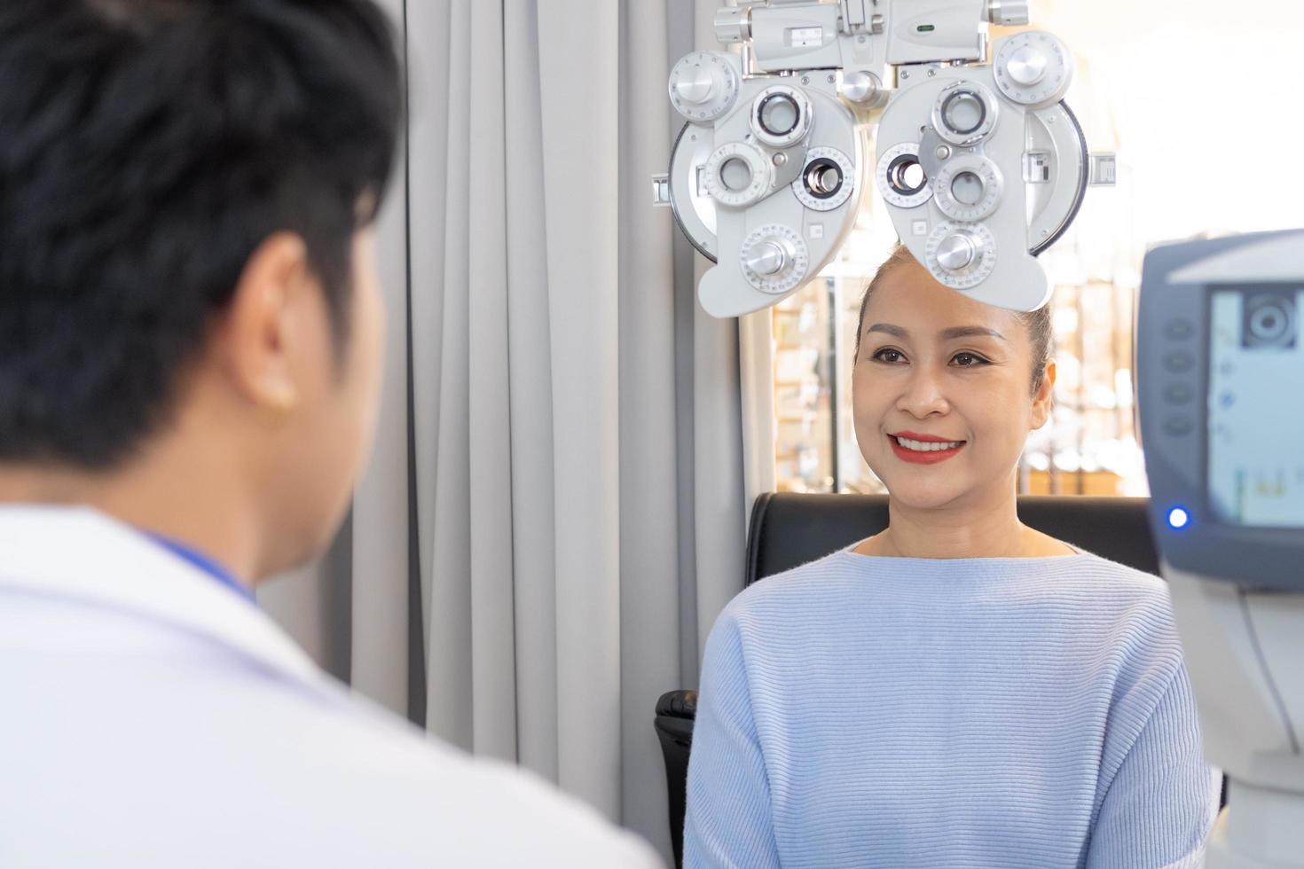 foco seletivo no equipamento de quadro de optometria. enquanto médico usando penlight e refração subjetiva para examinar o sistema visual ocular de mulheres idosas com máquina profissional antes de fazer óculos. foto