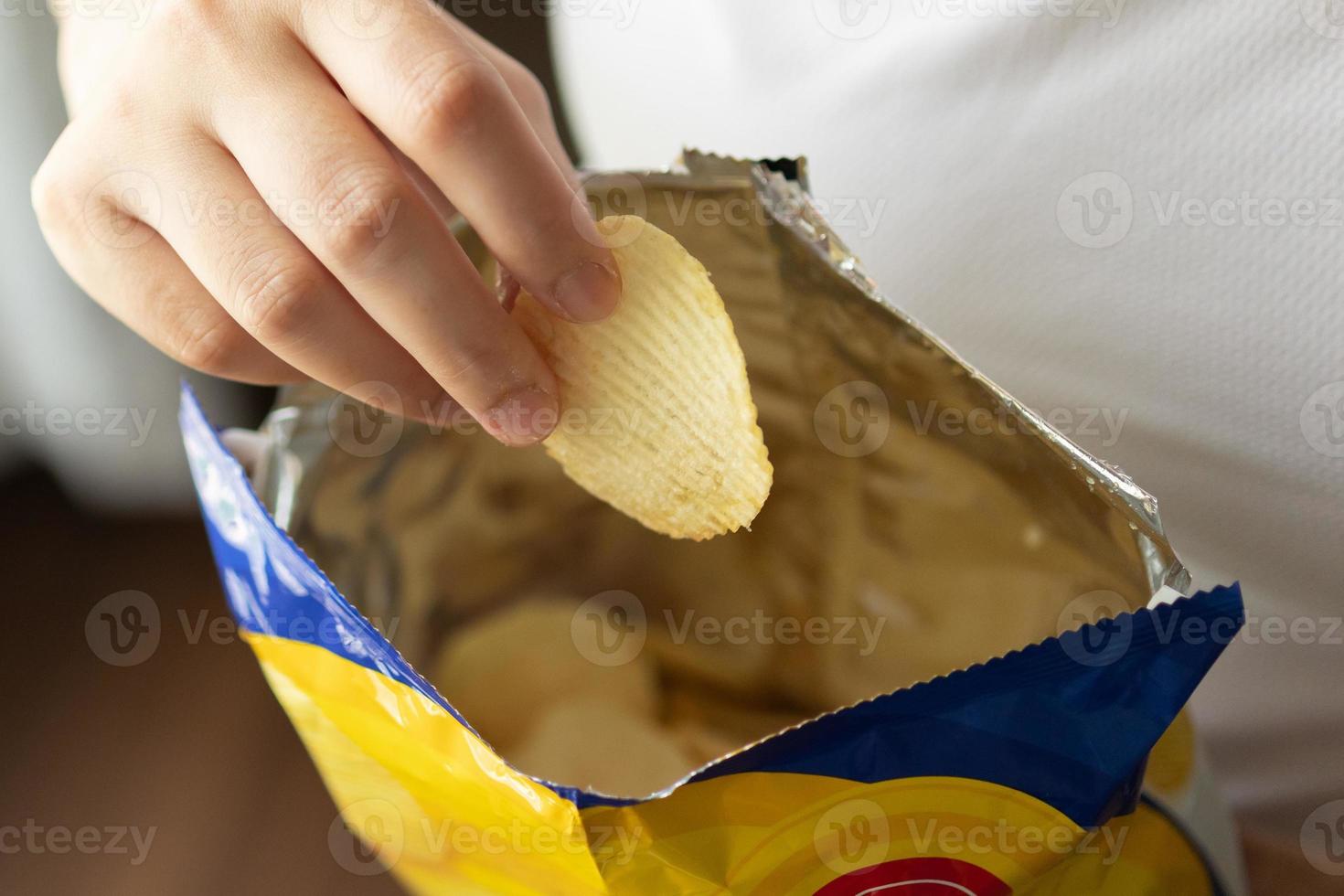 mão segure batatas fritas com saco de lanche foto