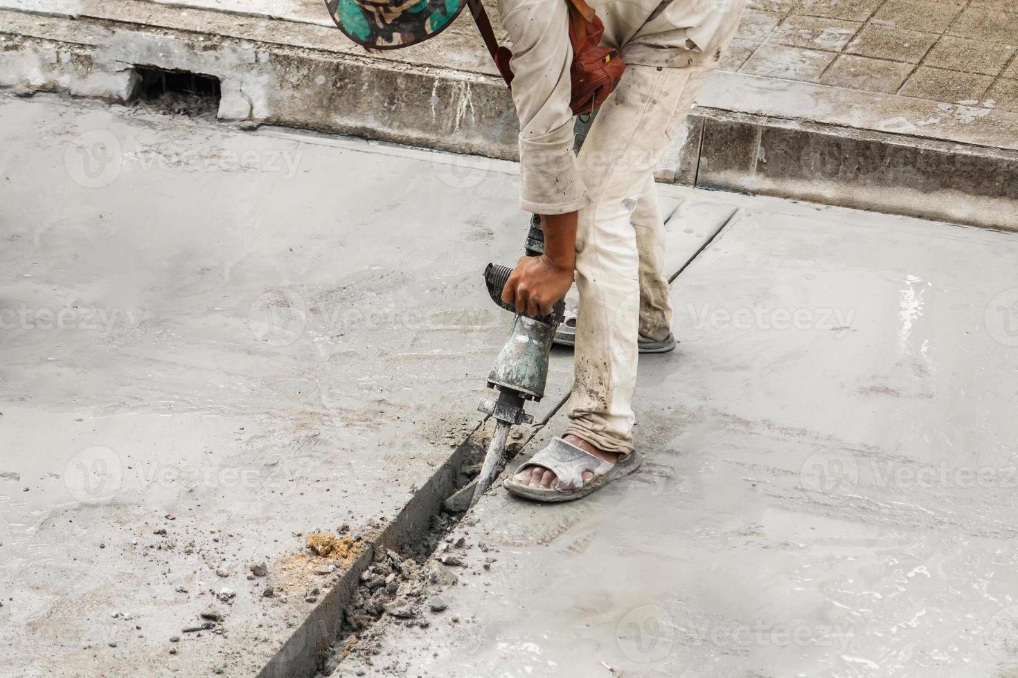 trabalhador da construção civil usando a superfície de concreto de perfuração de britadeira foto