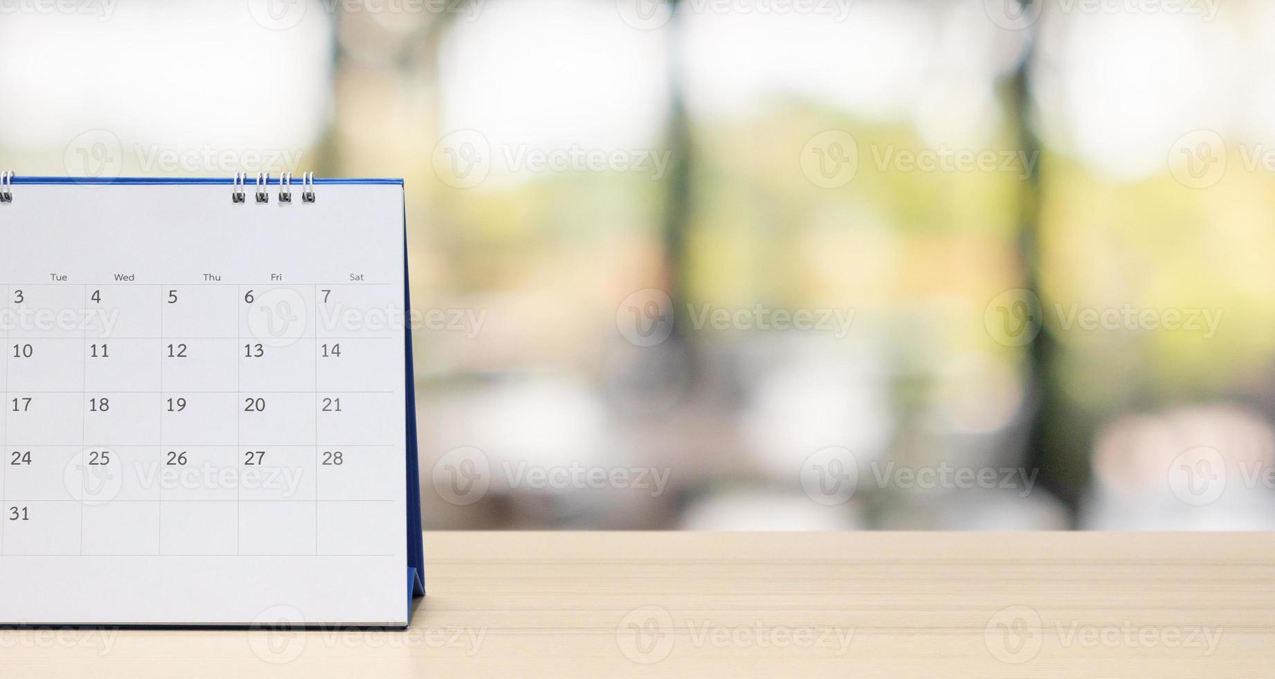 calendário de mesa de papel branco na mesa de madeira com nomeação de fundo bokeh turva e conceito de reunião de negócios foto