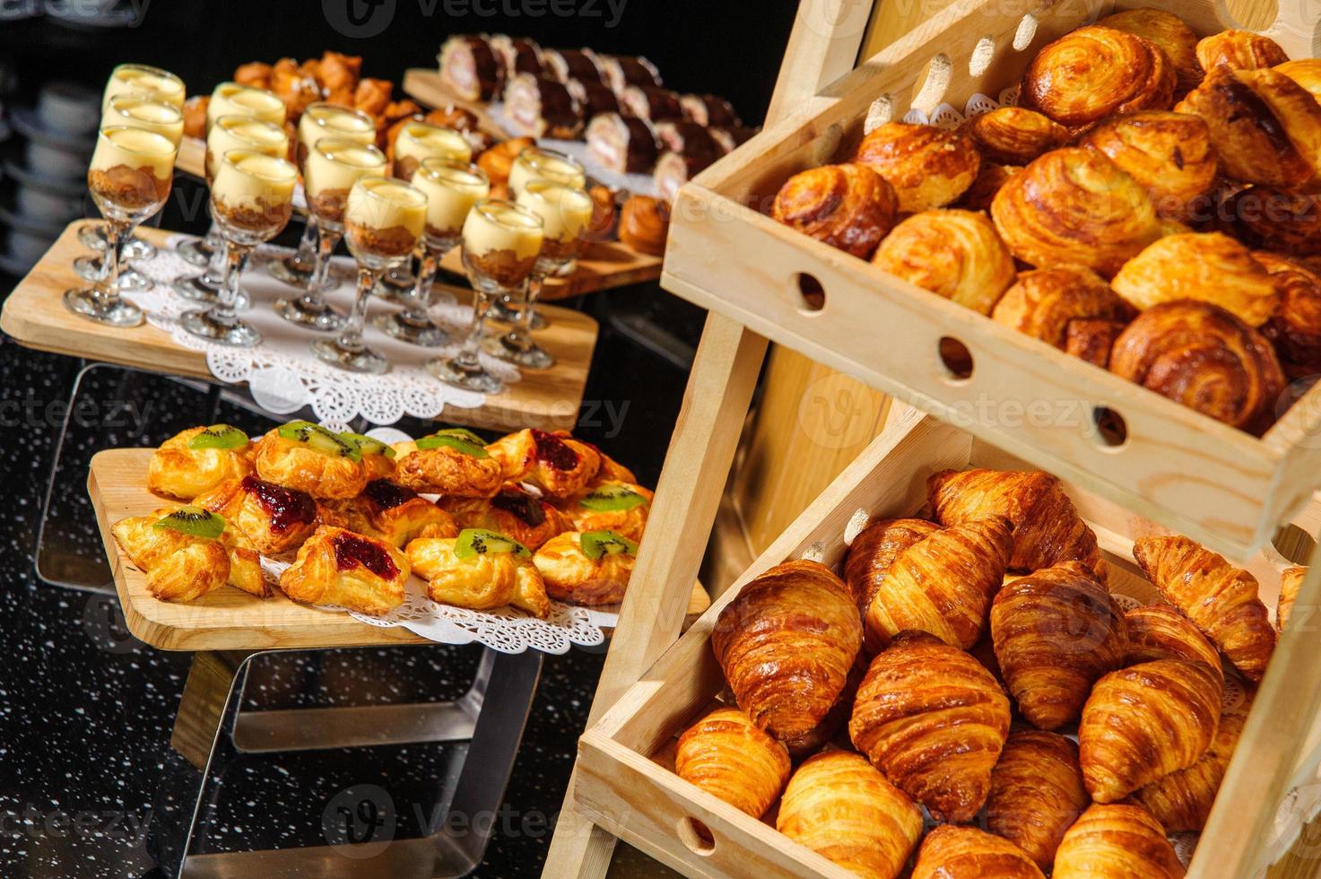 uma mesa de buffet com cestos de madeira cheios de croissants para exposição de produtos foto