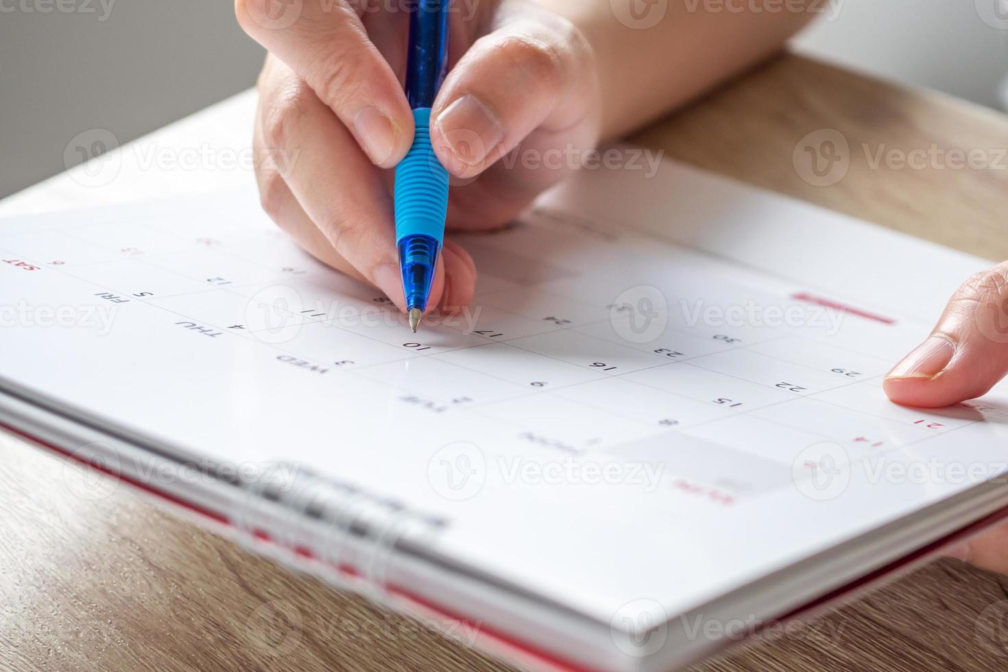 mão de mulher com caneta escrevendo na data do calendário conceito de reunião de planejamento de negócios foto