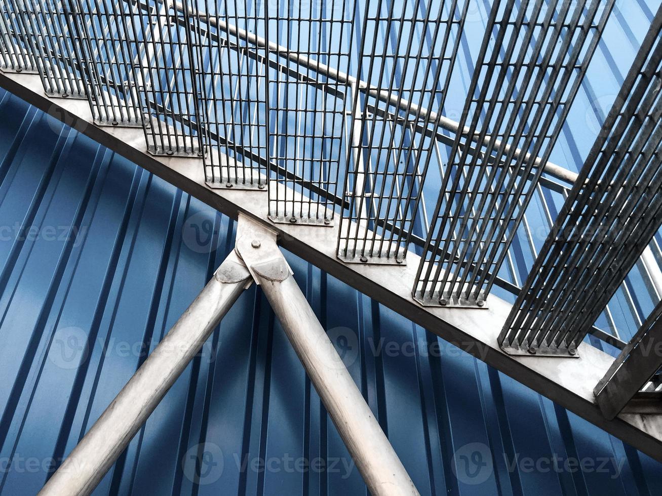 vista de perto de escadas de aço galvanizado contra um edifício de revestimento de metakl azul foto