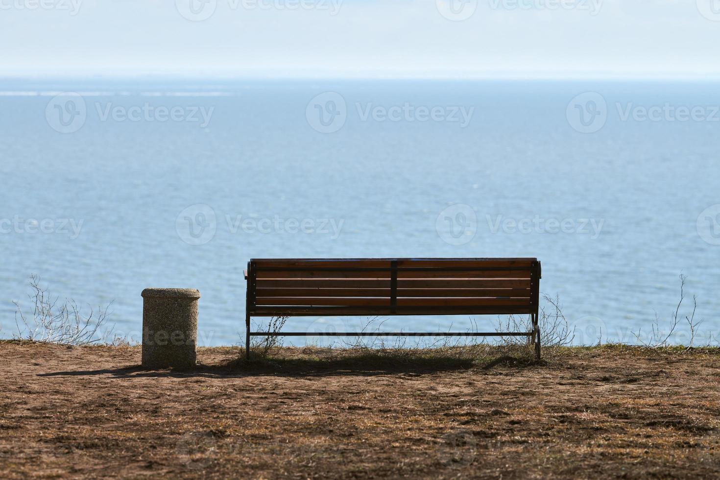 banco vazio com lixeira no penhasco antes do fundo do mar, lugar tranquilo e tranquilo para pensar sozinho foto