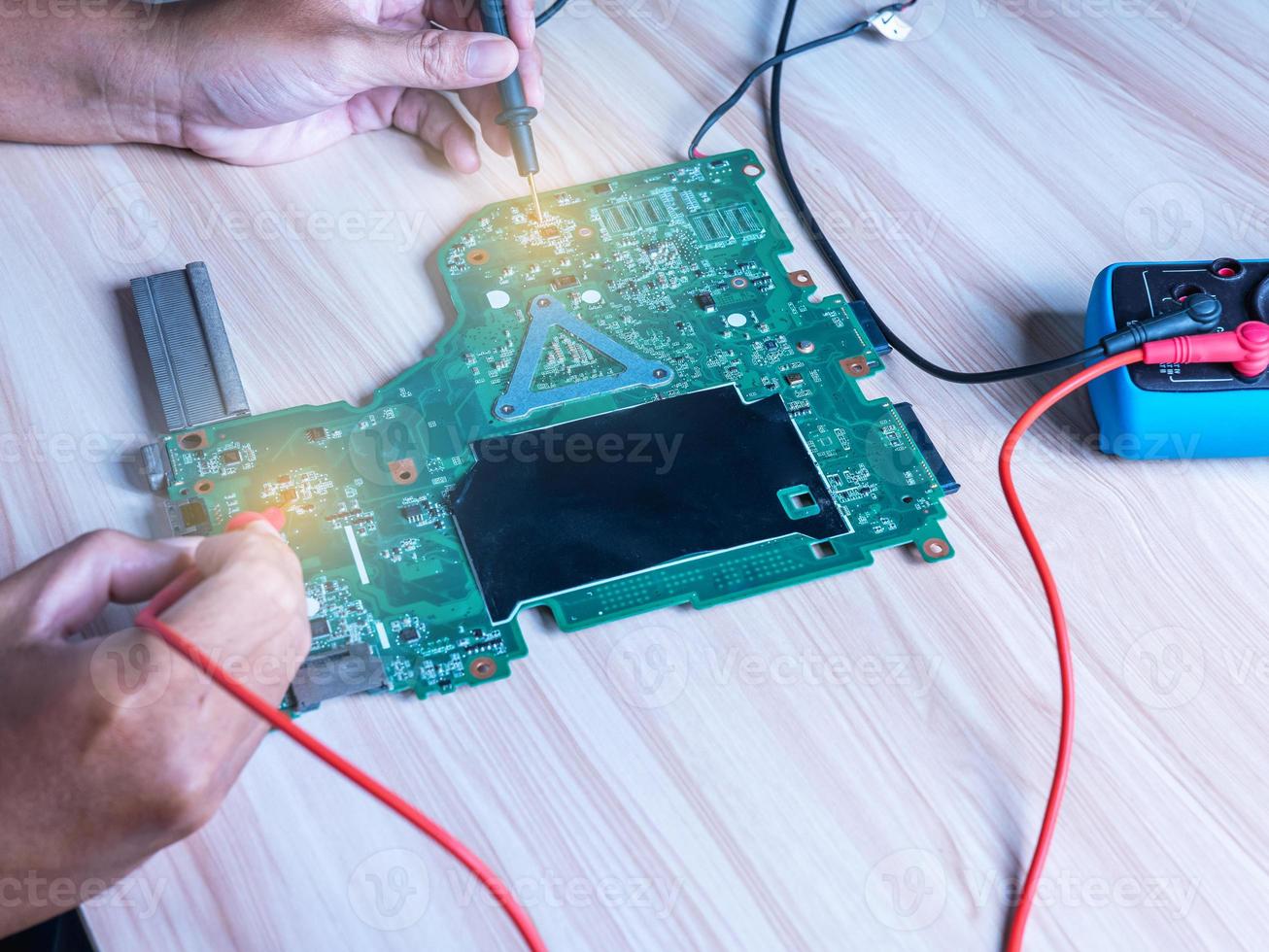 as mãos usam os fios vermelho e preto da tecnologia do multímetro usado para verificar o equipamento eletrônico verde da placa-mãe em vários pontos para encontrar o local da falha de reparo e voltar a usar. foto