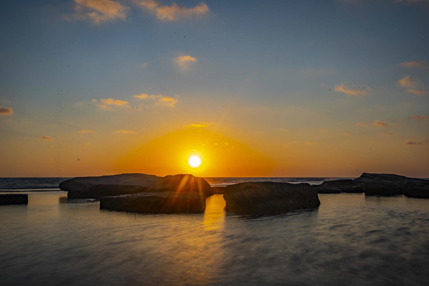 bela vista do mar com o sol brilhando em um céu azul ao fundo foto