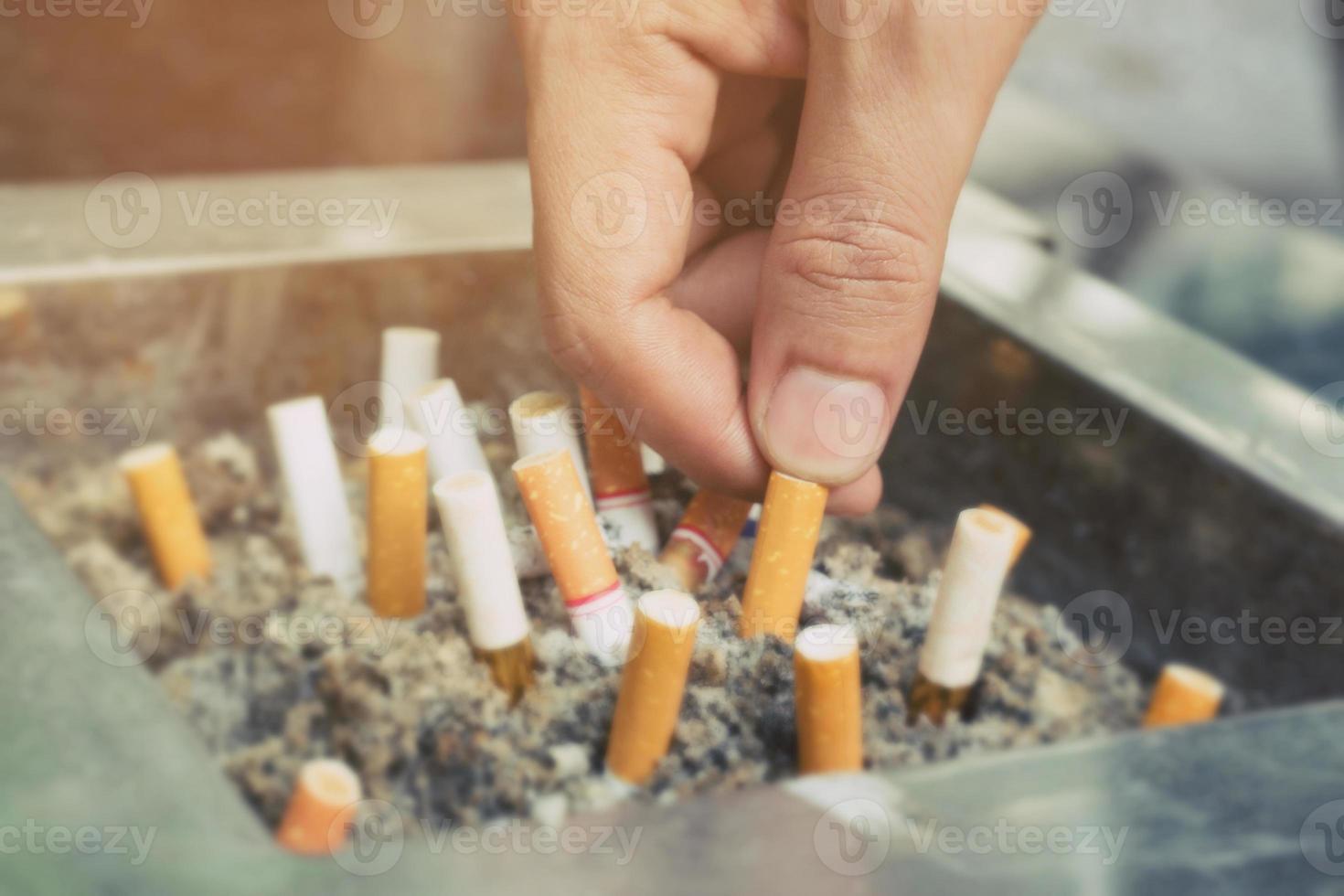 ponta de cigarro no cinzeiro. existem muitos tipos de pontas de cigarro na areia do cinzeiro. um cigarro não é bom para a saúde. foto