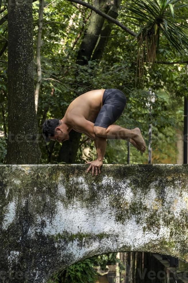 homem latino-americano fazendo postura de ioga, postura de ioga, abelha para trás prsthatah brahmara, floresta foto