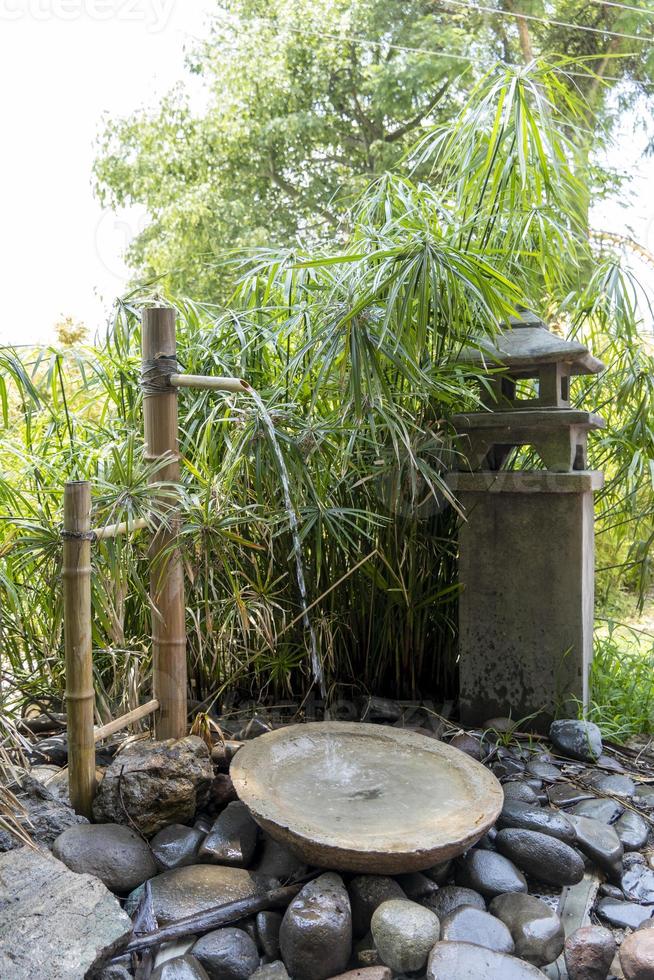 pequena fonte asiática com bambu, pedras do rio e água caindo, no méxico foto