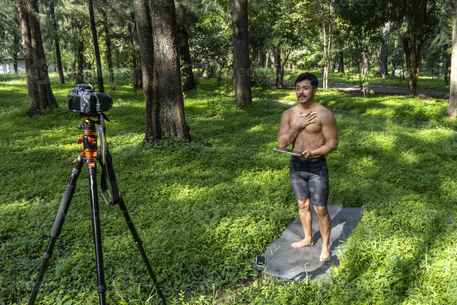 yogi masculino bonito ativo caminha em um parque passeando na floresta antes ou depois de um treino. aula de ioga jovem hispânico atlético com um tapete de fitness foto