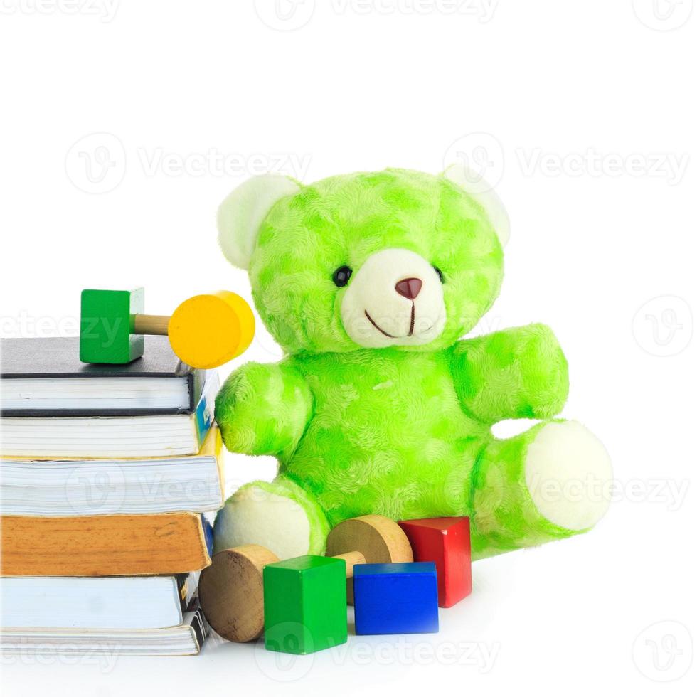 ursinho de pelúcia verde e pilha de livros sobre fundo branco foto