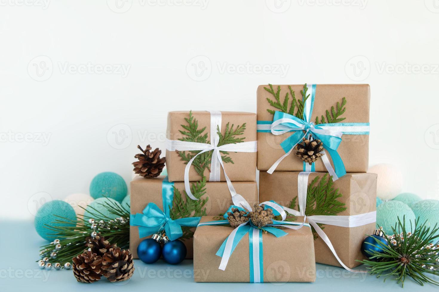caixas de presente de natal embrulhadas em papel artesanal, fitas azuis e  brancas sobre fundo azul