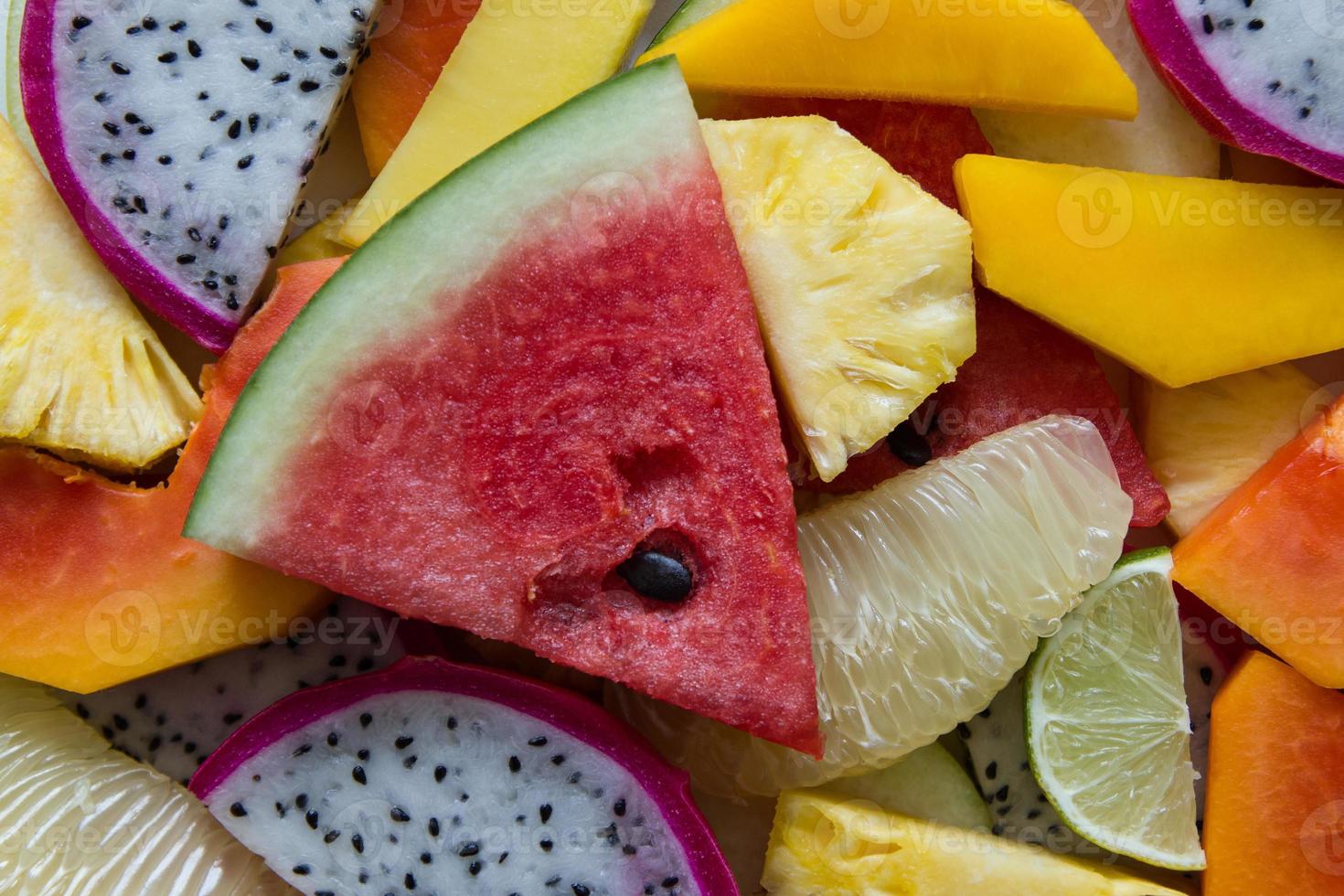 closeup misturado de frutas maduras e frescas para fundo colorido. fruta do dragão, abacaxi, mamão, limão, manga, pomelo, rambutan, melancia. foto