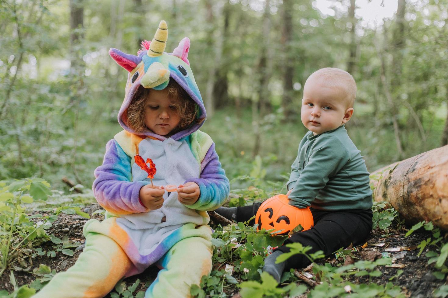 duas crianças andam na floresta com uma cesta de doces de halloween foto