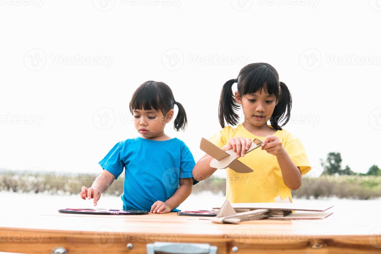 duas crianças brincando com avião de brinquedo de papelão no parque durante o dia. conceito de jogo feliz. criança se divertindo ao ar livre. foto