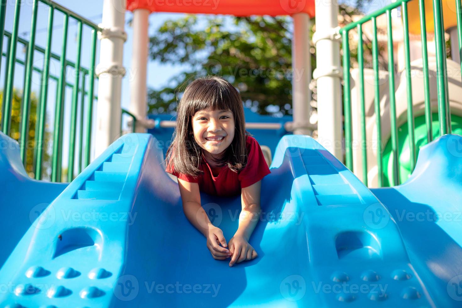 menina bonitinha se divertindo em um playground ao ar livre no verão foto