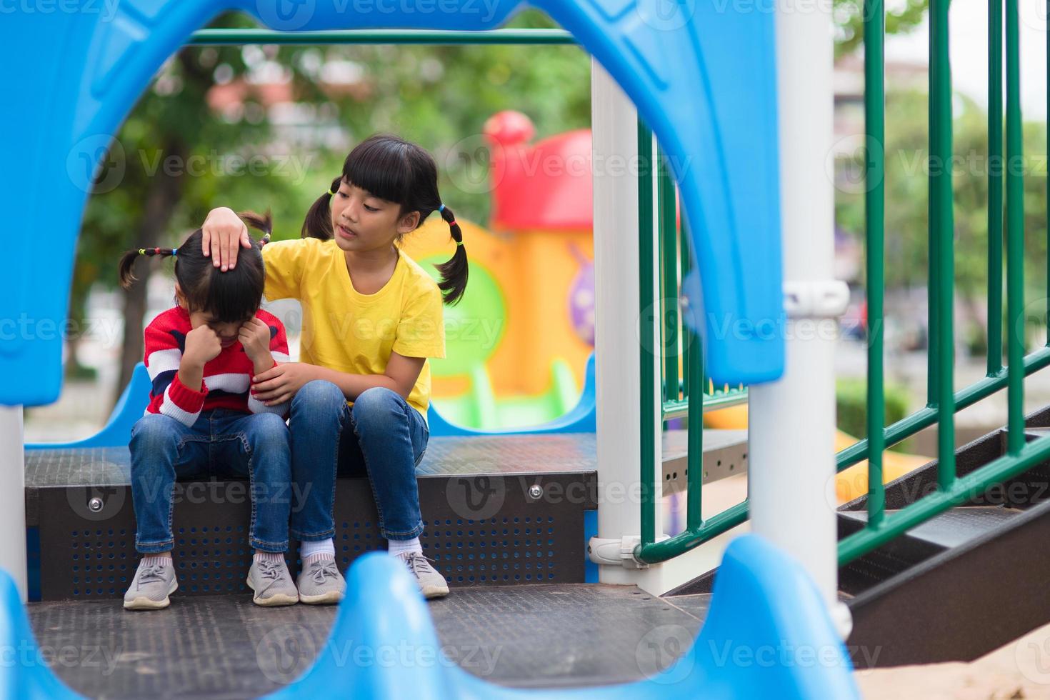 menina confortando sua irmã no playground foto
